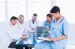 Female surgeon looking at reports with colleagues in meeting at a medical office